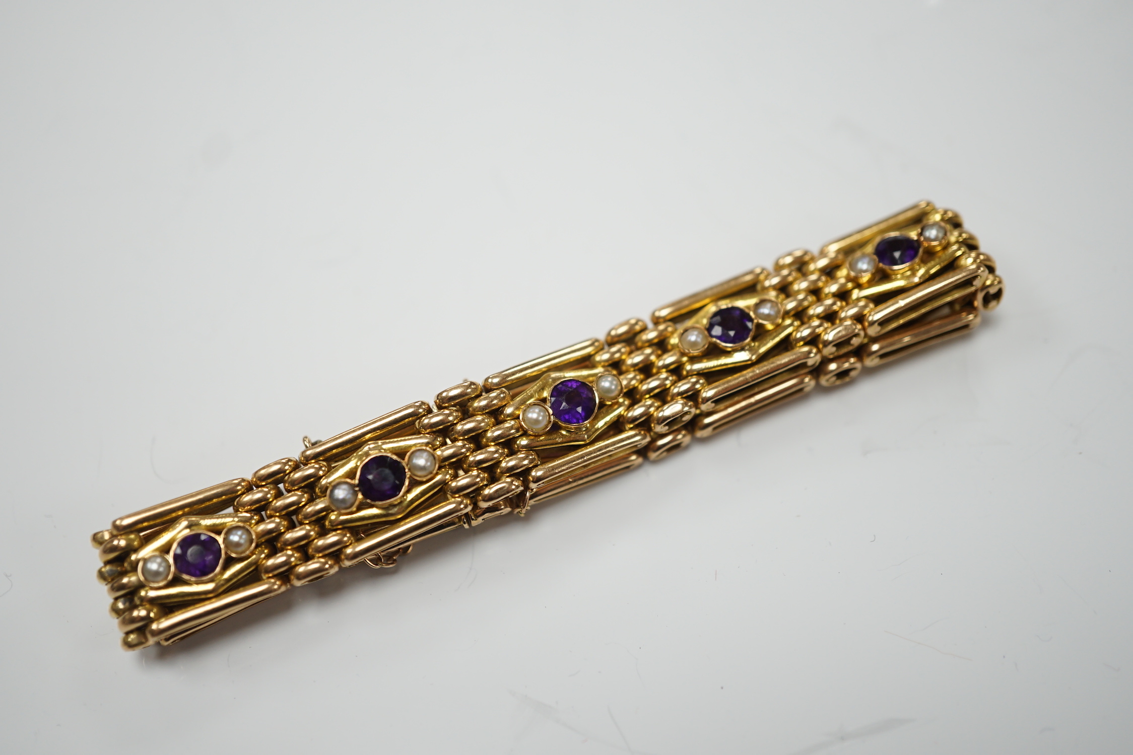 An Edwardian 15ct, amethyst and seed pearl set gate link bracelet, 18cm